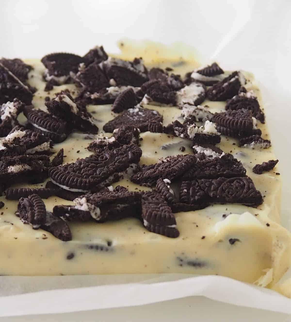 Uncut slab of White chocolate and Oreo fudge sitting on a piece of baking paper.