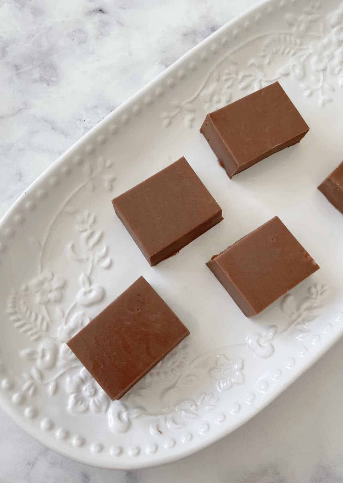 pieces of chocolate fudge on a white decorative serving tray.