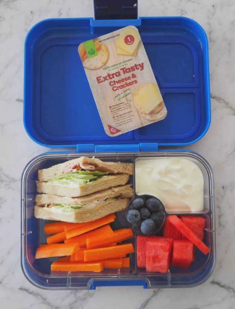 lunchbox with sandwich, fruit, yoghurt and cheese and crackers.