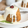 Mini Christmas pudding on a white plate with custard over the top