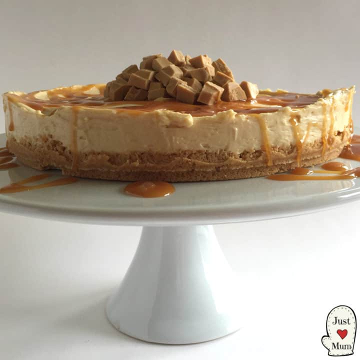 Caramilk Cheesecake with dripping topping all over sits on a cake stand.