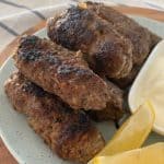 Side view of beef koftas on a plate with lemon