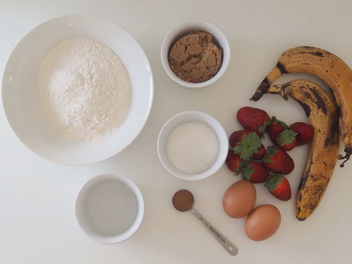 Ingredients needed to make Banana and Strawberry Bread on a bench top.