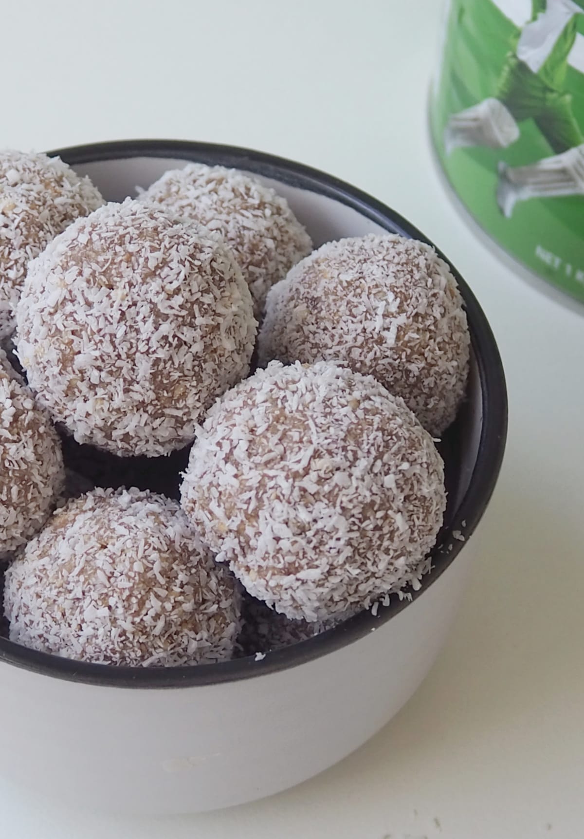 Overhead view of Milo Balls in a white bowl. in the background there is a tin of Milo.