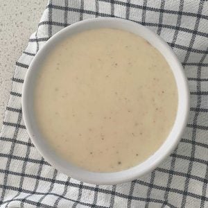 Cheese Sauce in a white ramekin sitting on a blue check towel