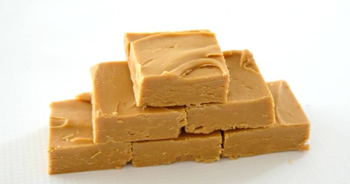 six pieces of caramel fudge stacked in a pyramid on a white background