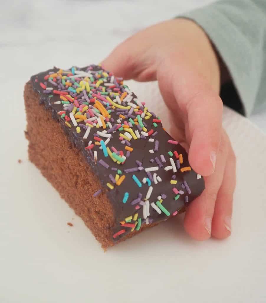 Child reaching for a slice of chocolate cake