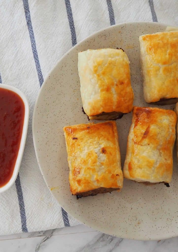 overhead view of sausage rolls on a stone coloured plate