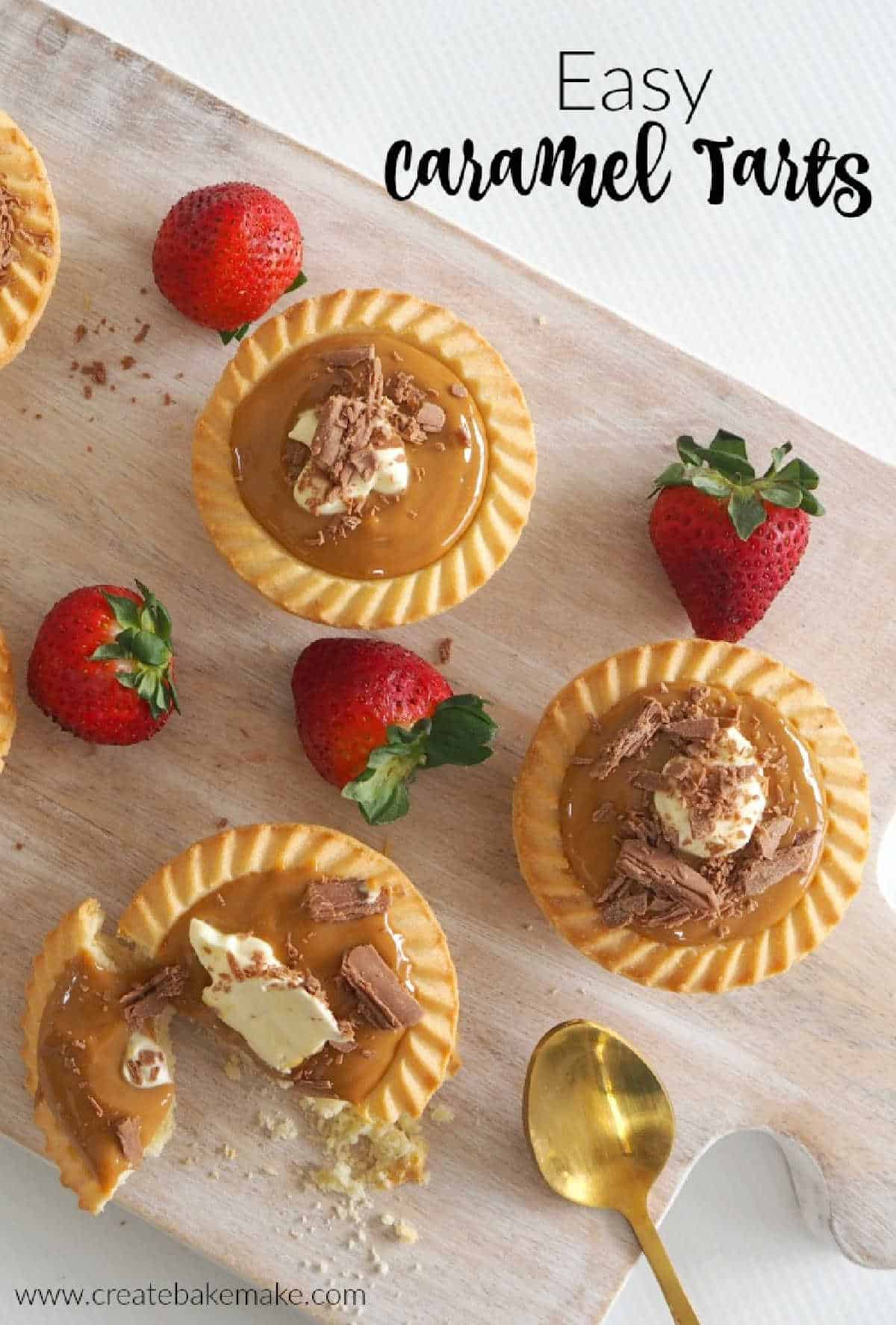 Overhead view of 3 caramel tarts with strawberries on a wooden board