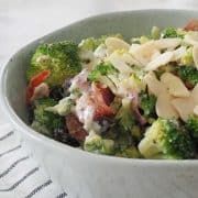 Side view of broccoli salad in a green speckled bowl on marble background