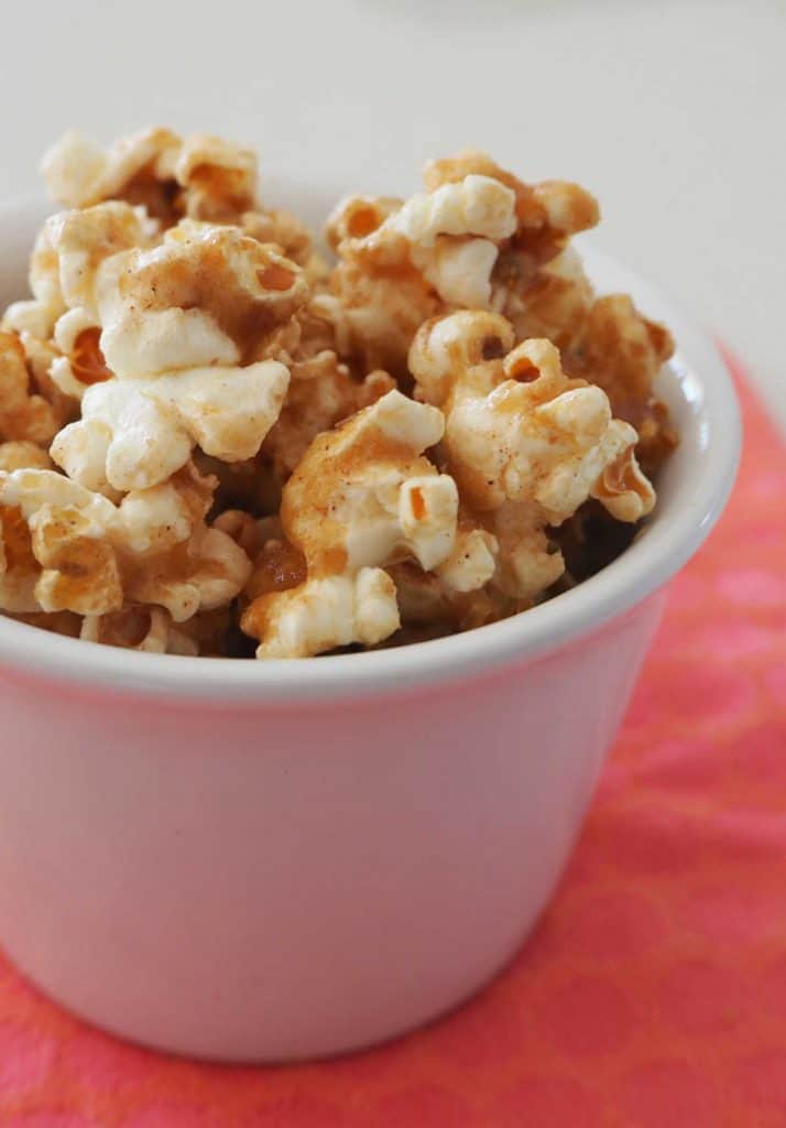 Cinnamon popcorn in a white bowl on a pink background