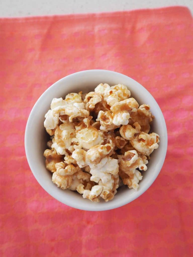 overhead view of Cinnamon popcorn in a white bowl on a pink background