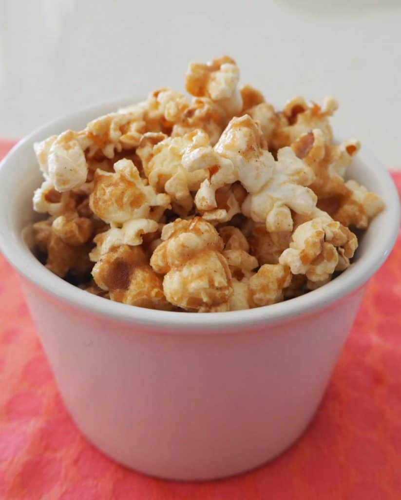 Cinnamon popcorn in a white bowl on a pink background