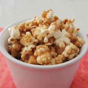 Cinnamon popcorn in a white bowl on a pink background