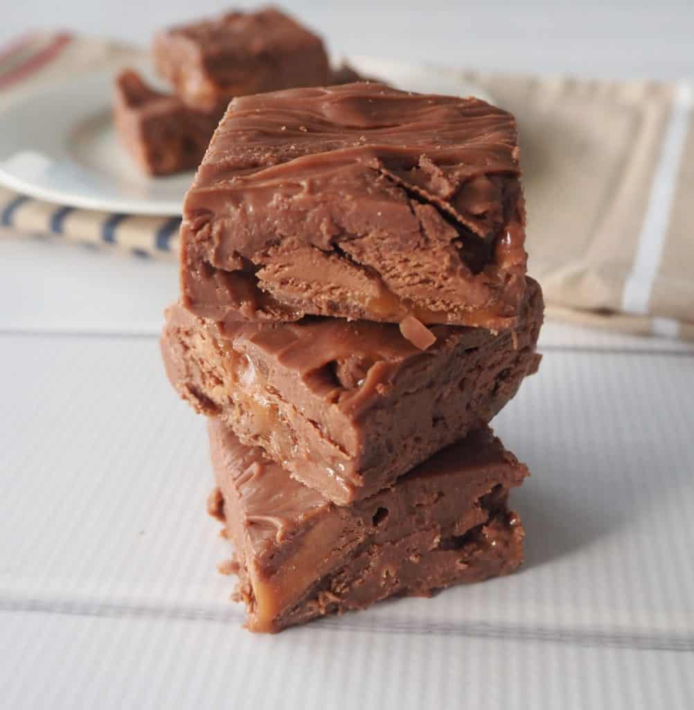 close up of three pieces of Mars Bar Fudge stacked on a white background