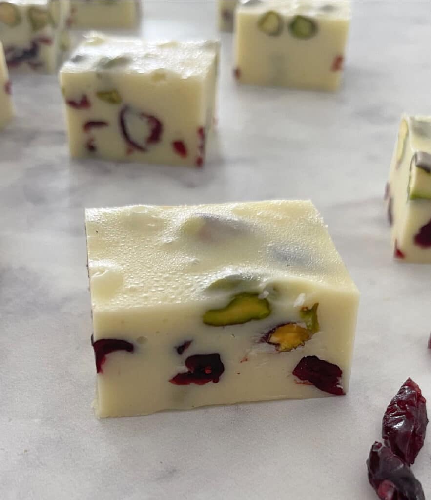 one piece of 4 ingredient christmas fudge on a marble background