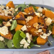 close up side view Roast Pumpkin Salad on a blue serving plate with a marble background