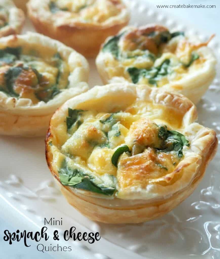 Close up side view of spinach and feta mini quiche on a white platter.