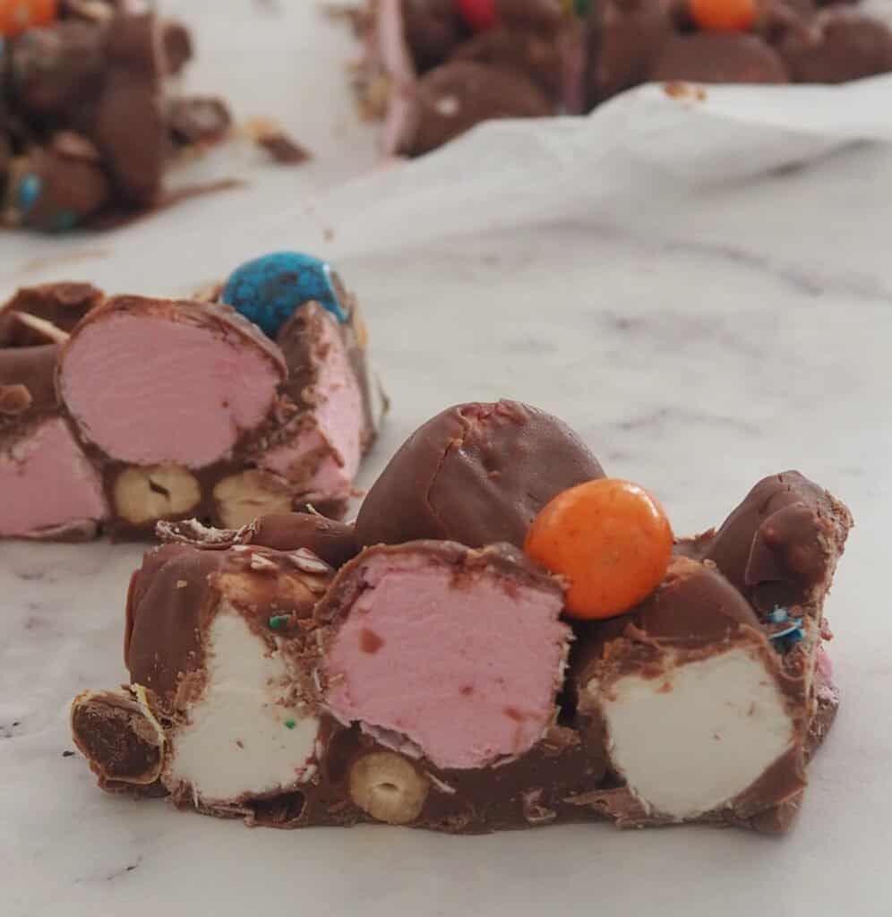 Slice of rocky road sitting on baking paper with more rocky road behind it.