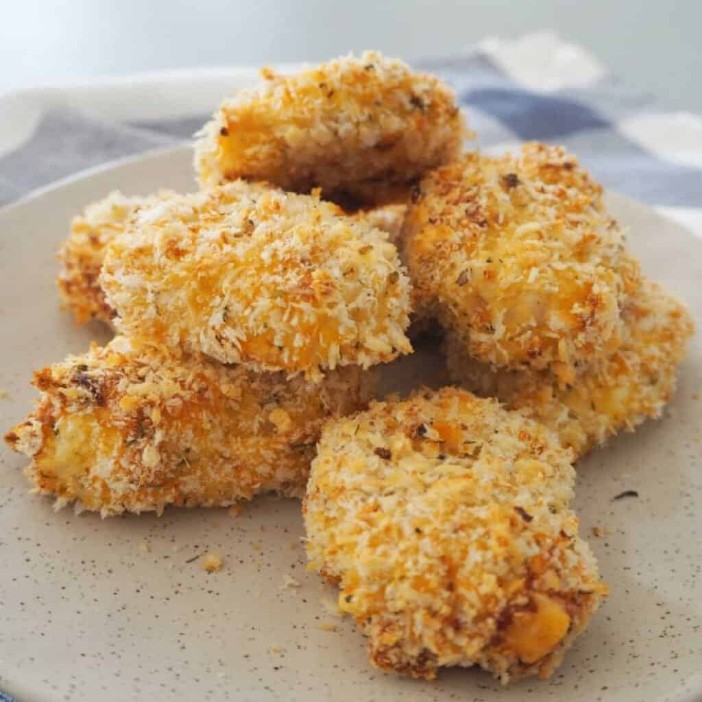 Side view of Homemade chicken nuggets piled on a speckled plate.