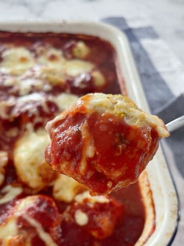 spoon holding a baked chicken parma ball.