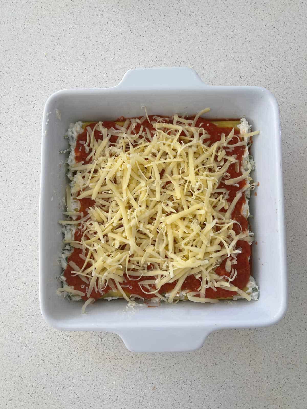 spinach and ricotta cannelloni in white baking dish ready for the oven.
