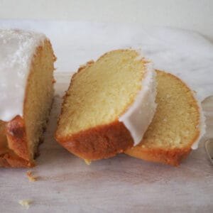 Lemon Butter Cake Sliced and sitting on a pale wooden board.