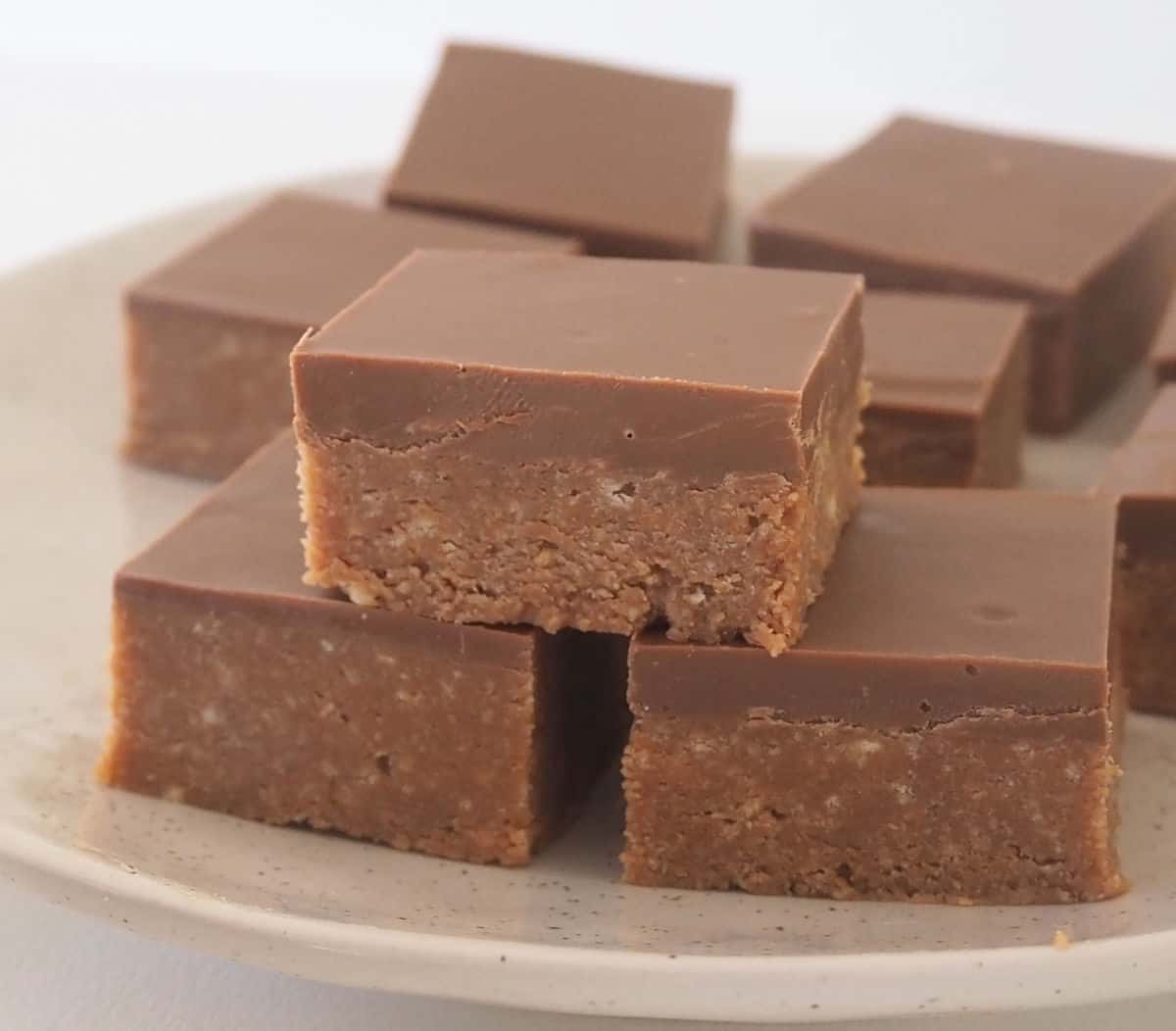 Pieces of Caramello Slice stacked on a speckled plate.