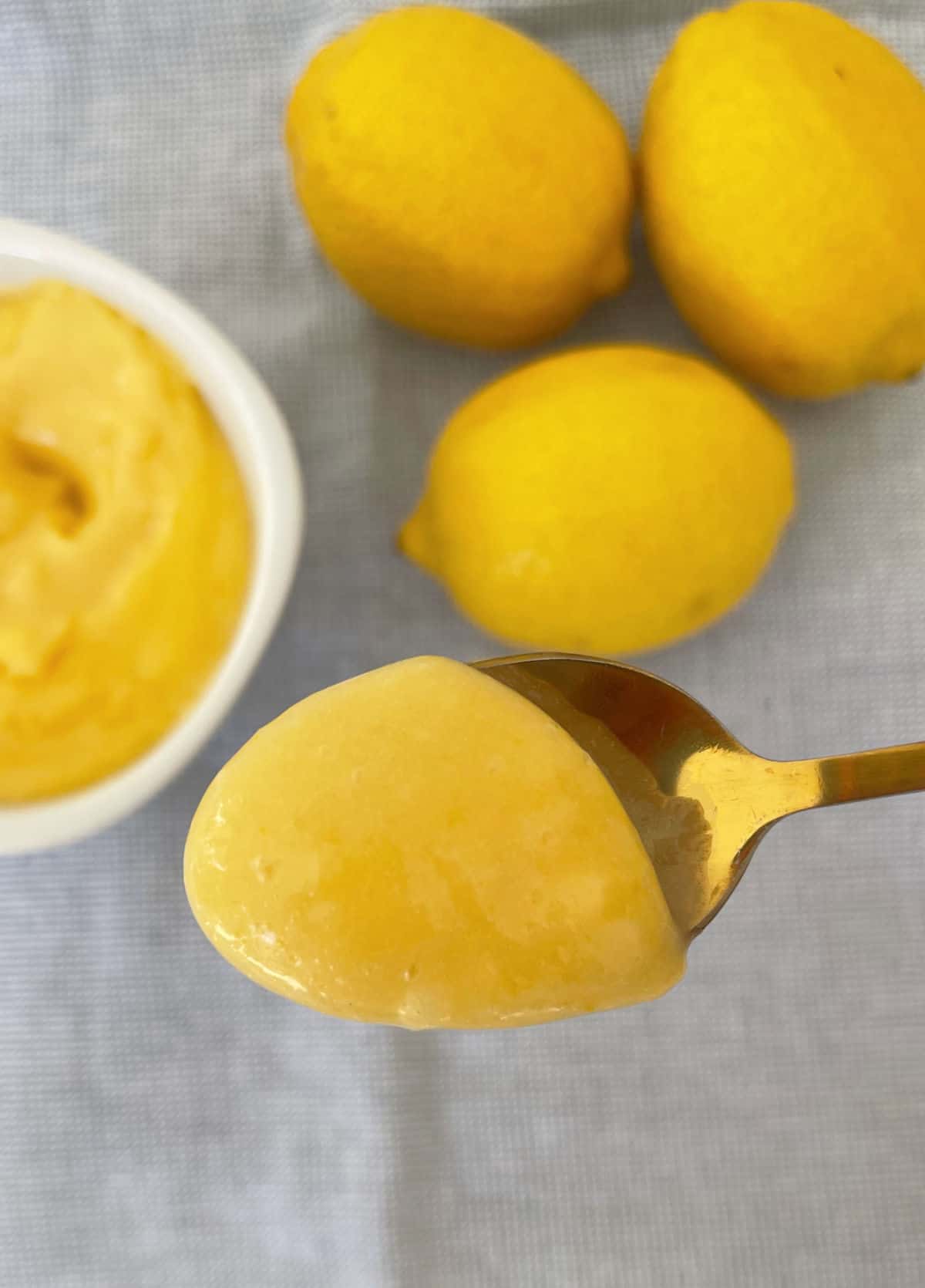 gold spoon holding up lemon curd.