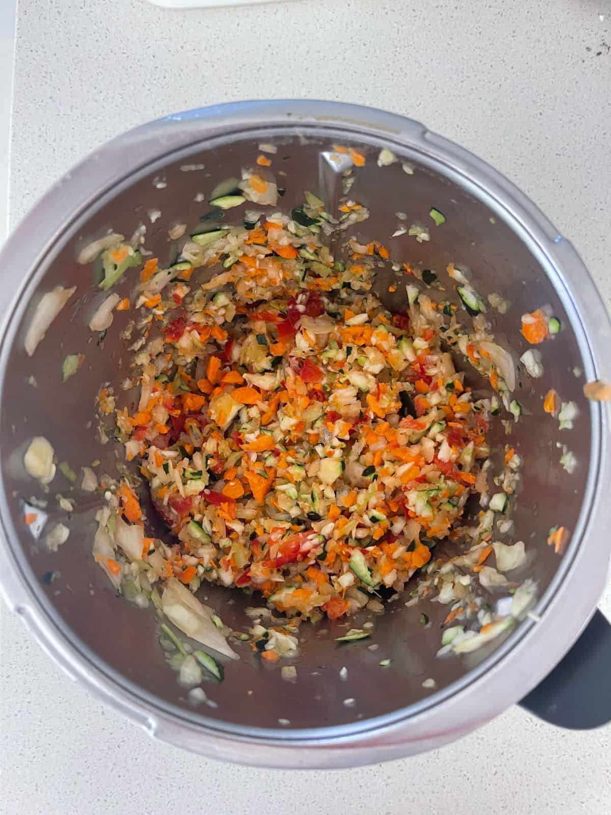 Grated vegetable in a Thermomix bowl.