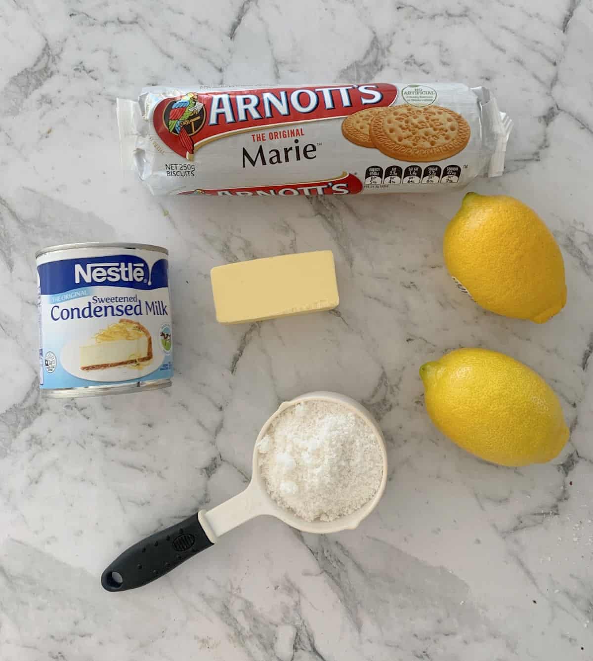 Ingredients to make Thermomix Lemon Slice sitting on a marble look bench top.