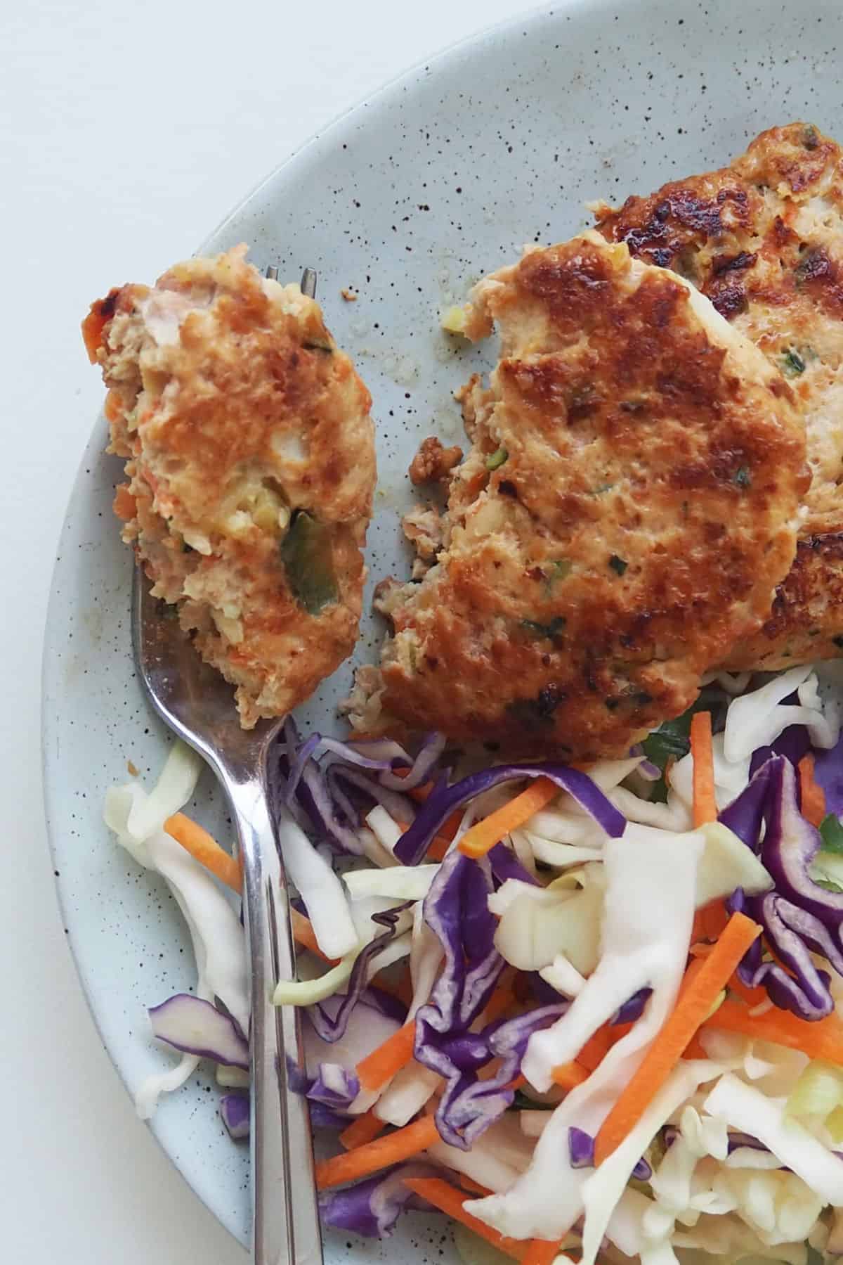 Chicken rissole cut in half on a green plate with coleslaw.