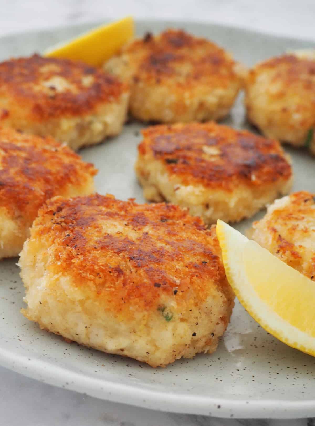 Plate of Fish Cakes with lemon wedges.