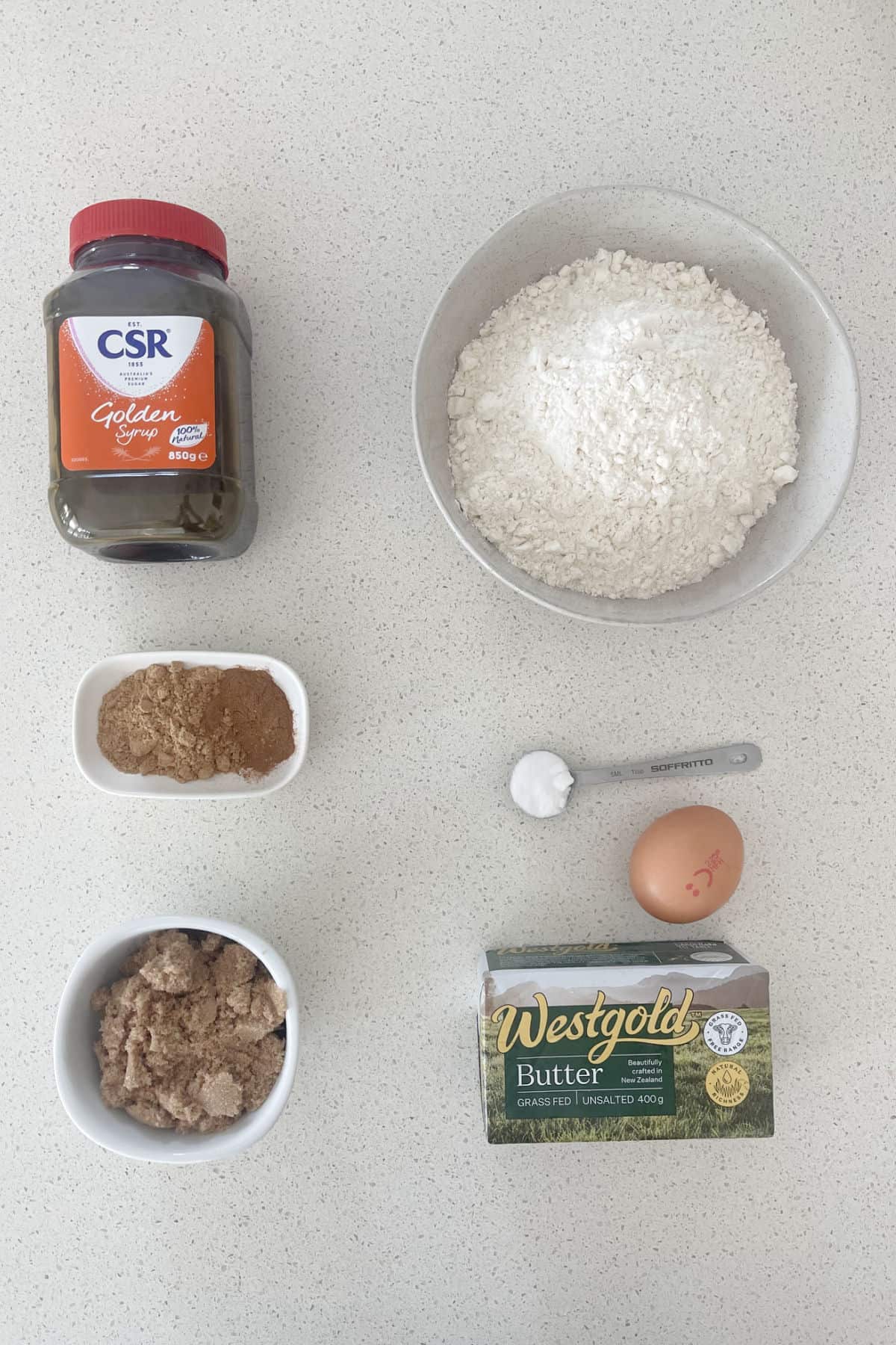 Ingredients to make Gingerbread on a white speckled bench.