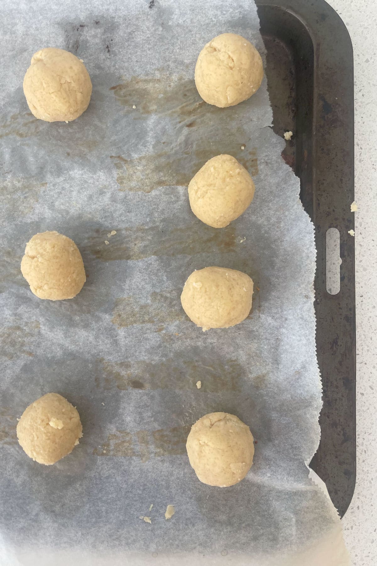 Balls of honey biscuits on a baking tray.