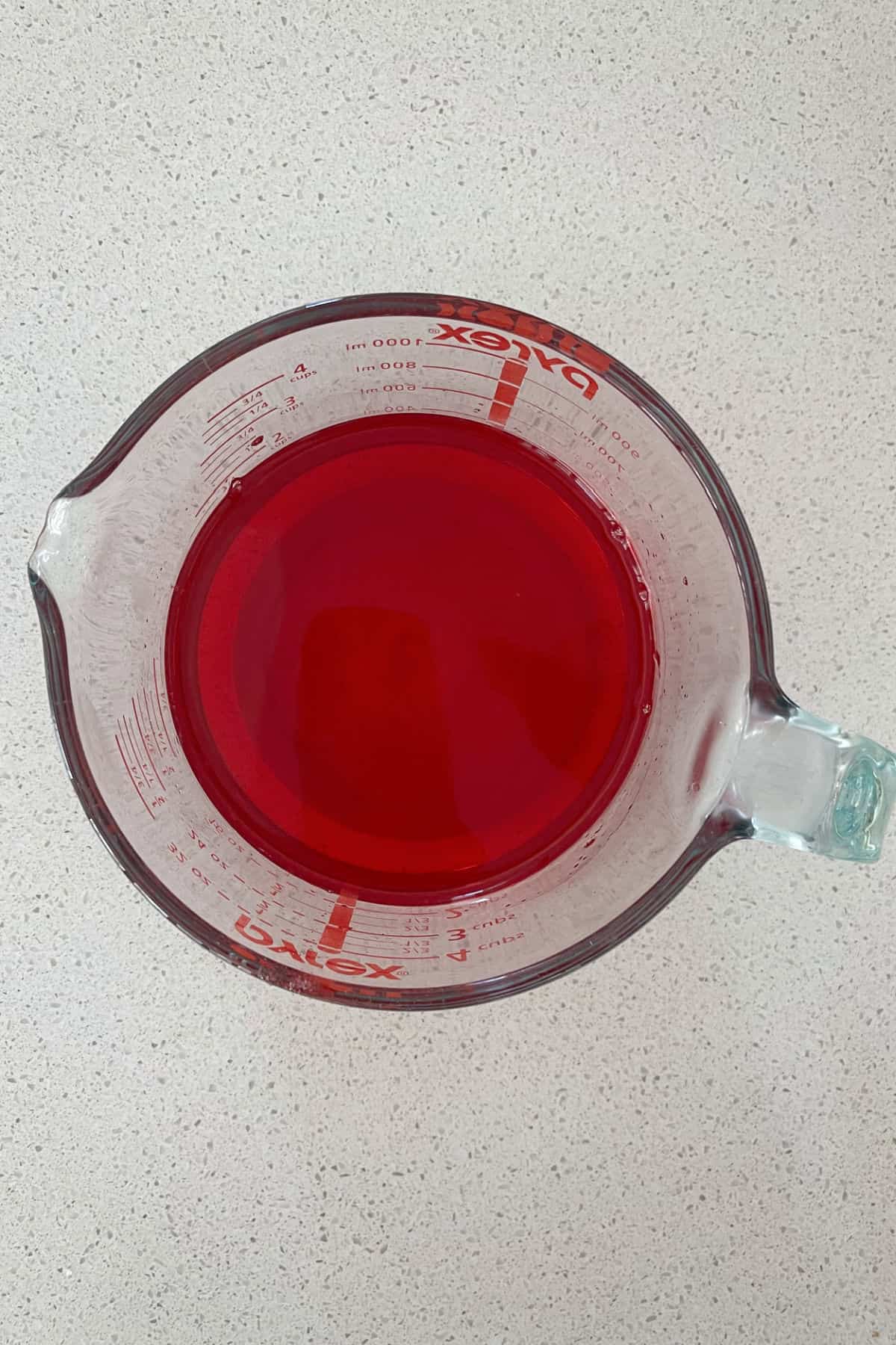 Strawberry jelly in a glass measuring jug.