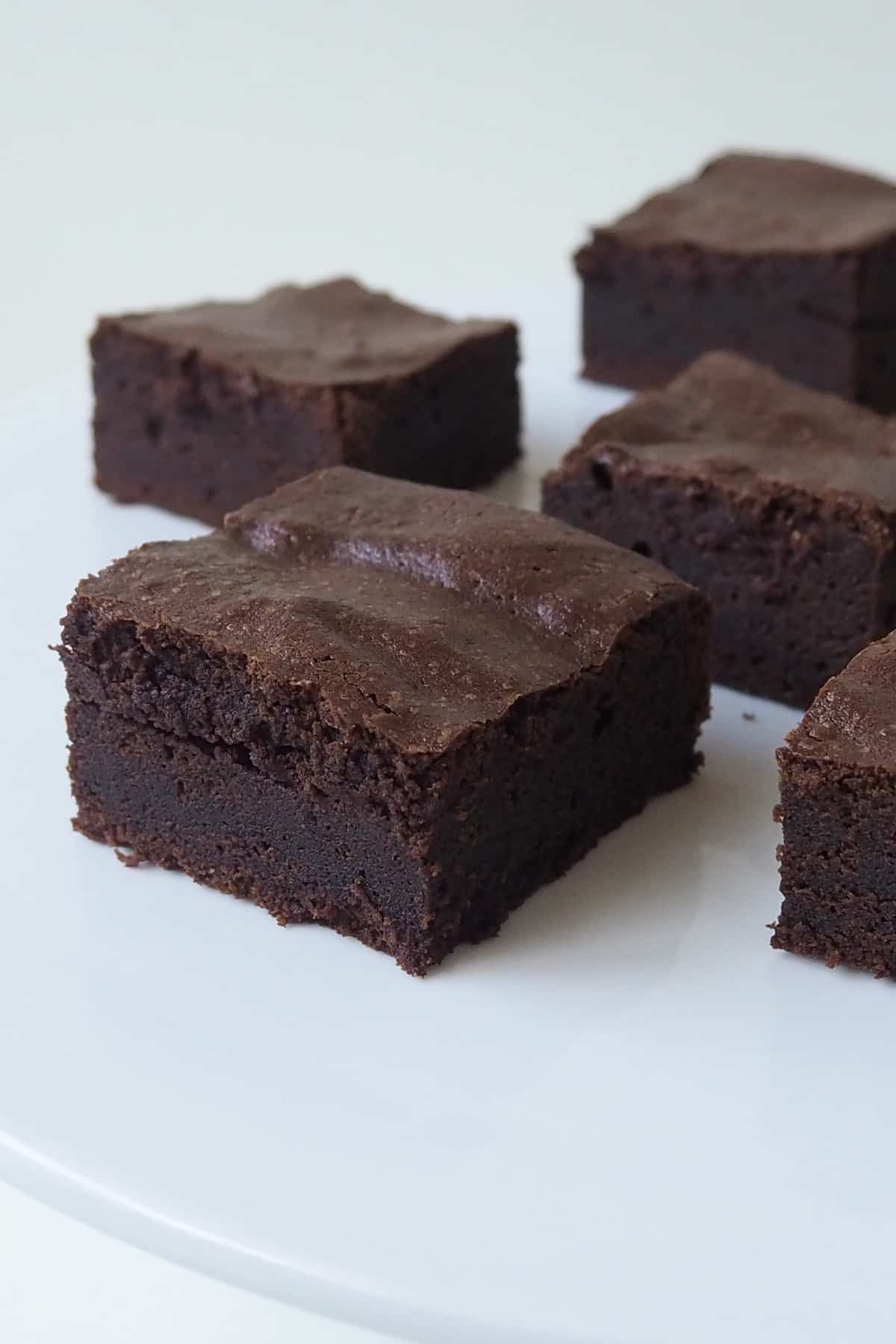 Side view of Slices of Thermomix Brownies on a white bench.