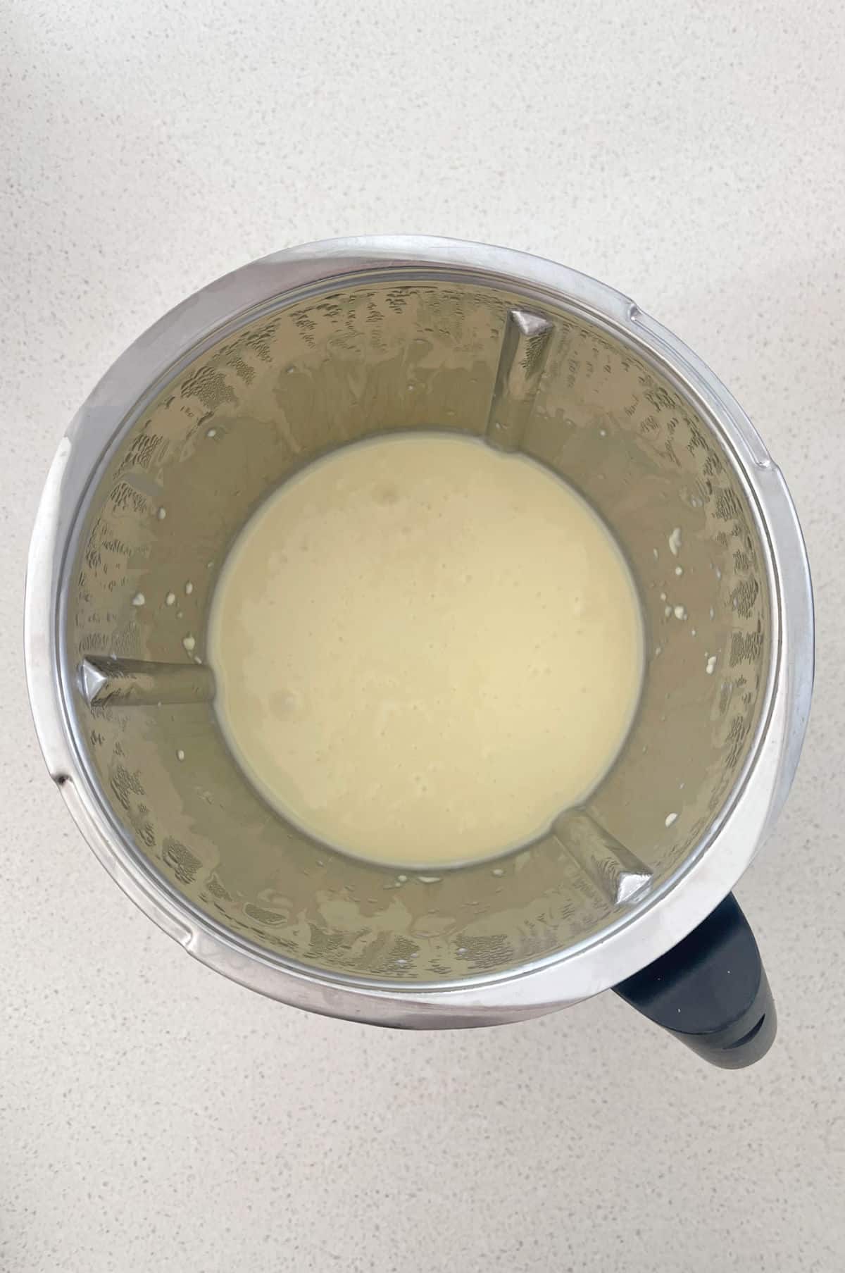 Melted white chocolate and sweetened condensed milk in a thermomix bowl.
