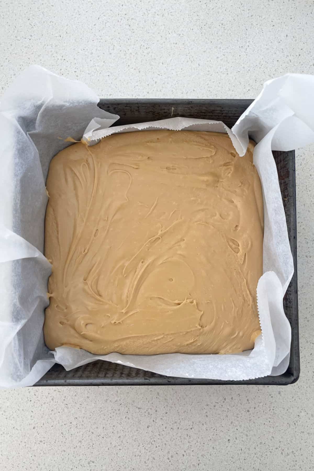 Biscoff fudge poured into a baking tin.