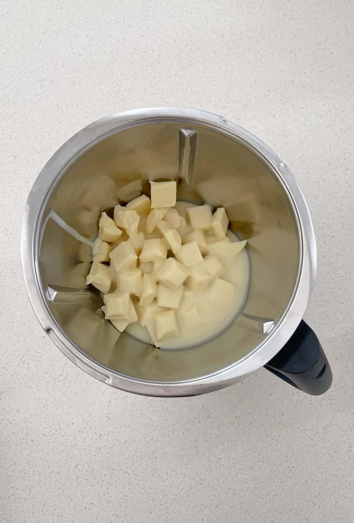 White chocolate and sweetened condensed milk in a thermomix bowl.