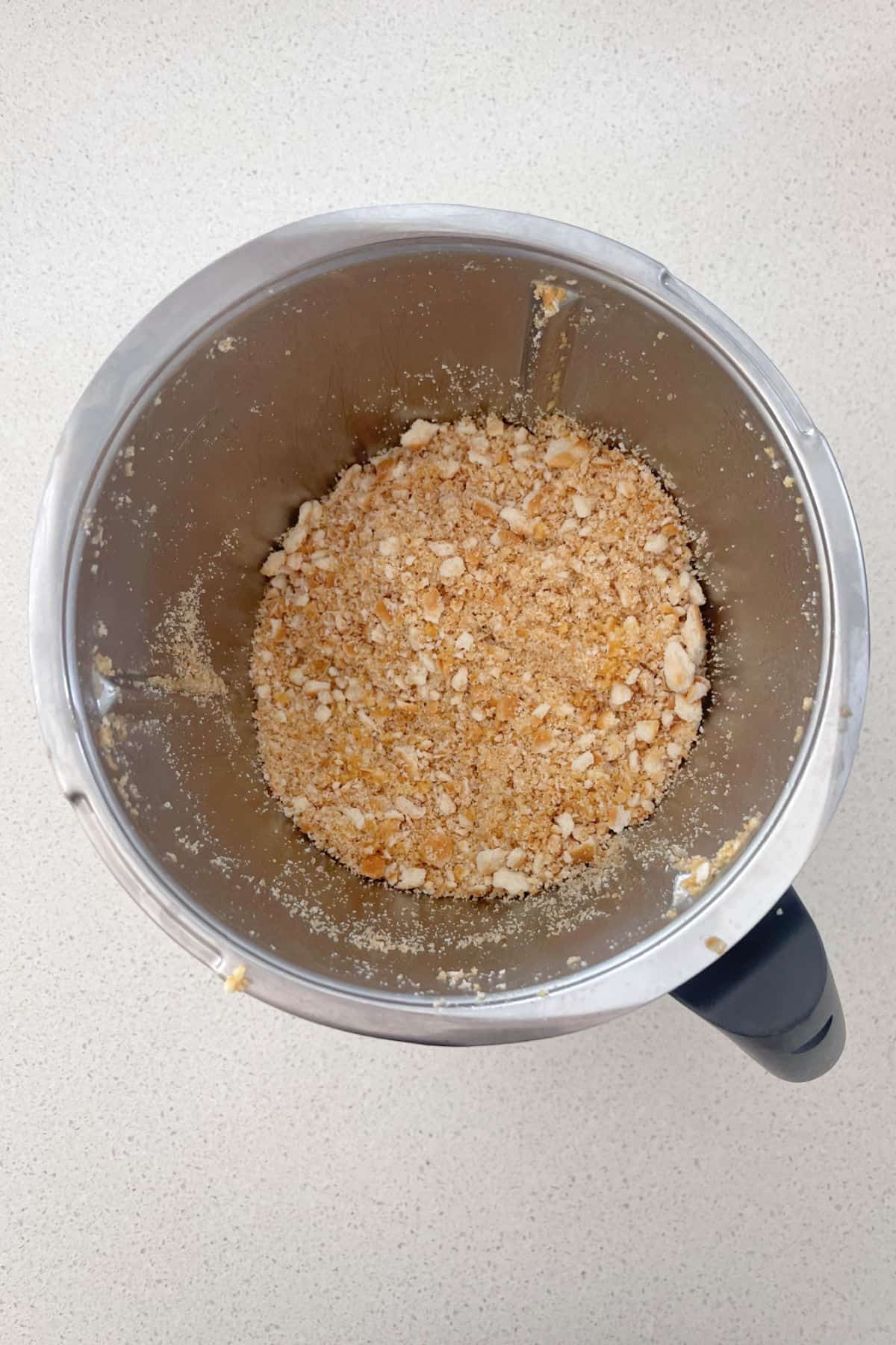 Crushed biscuits and butter in a Thermomix bowl.