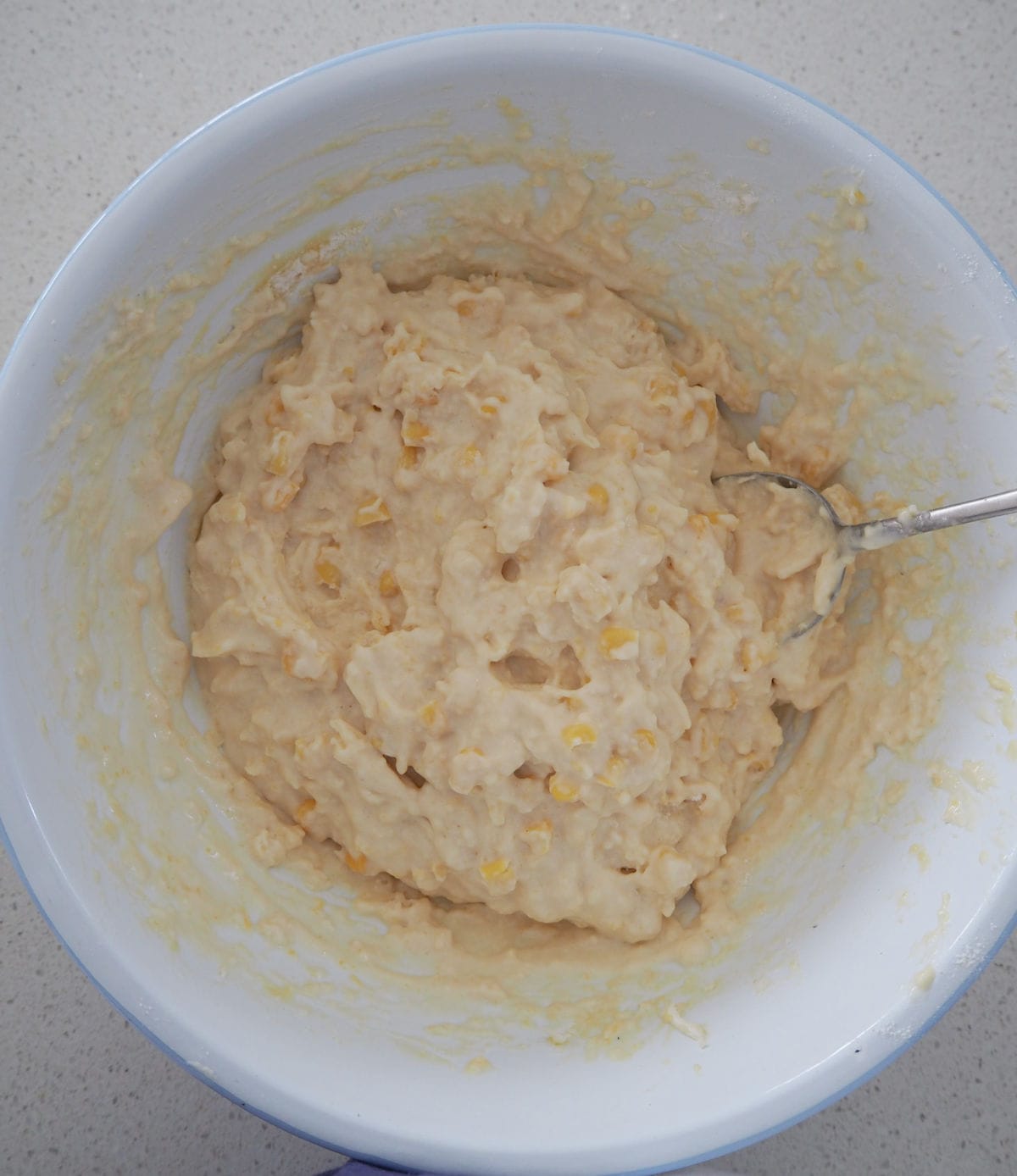 Cheese and corn muffin mixture combined in a white bowl.