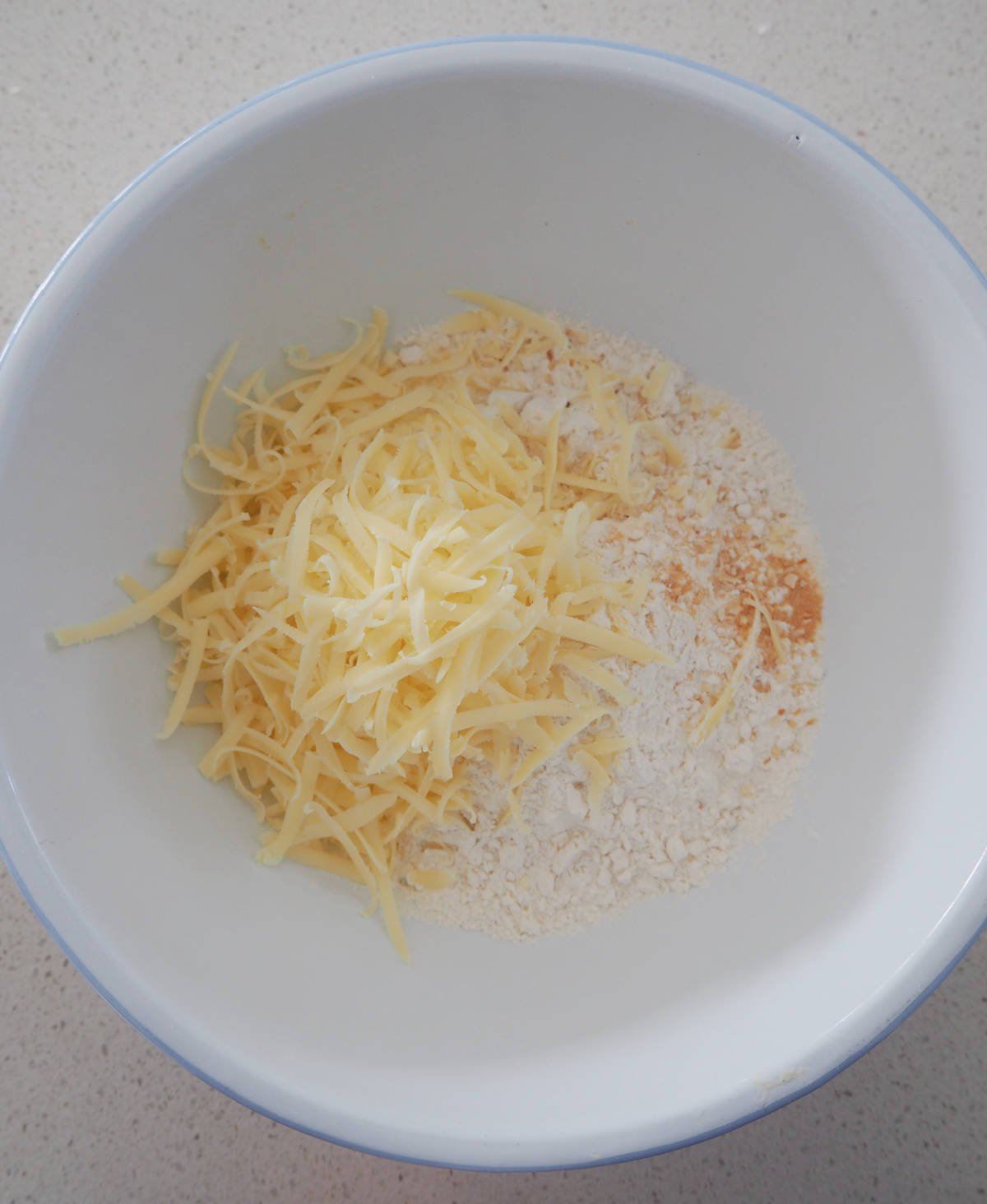 Cheese and Corn Muffin mixture in a white bowl before being mixed together.