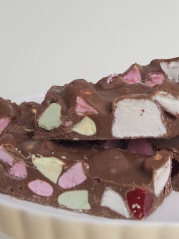 Pieces of Clinkers Rocky Road stacked on top of each other sitting on a cream serving plate.