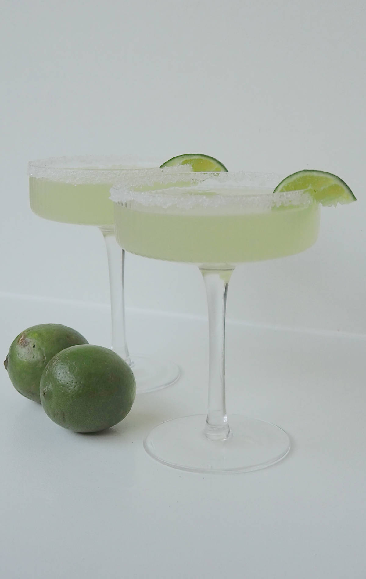 Two Margaritas made using a thermomix in glasses garnished with salt and lime.