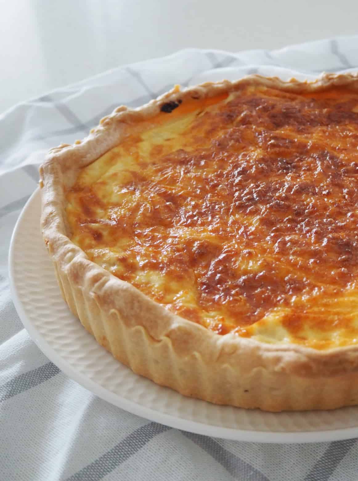 Side view of a Quiche Lorraine sitting on a white plate.