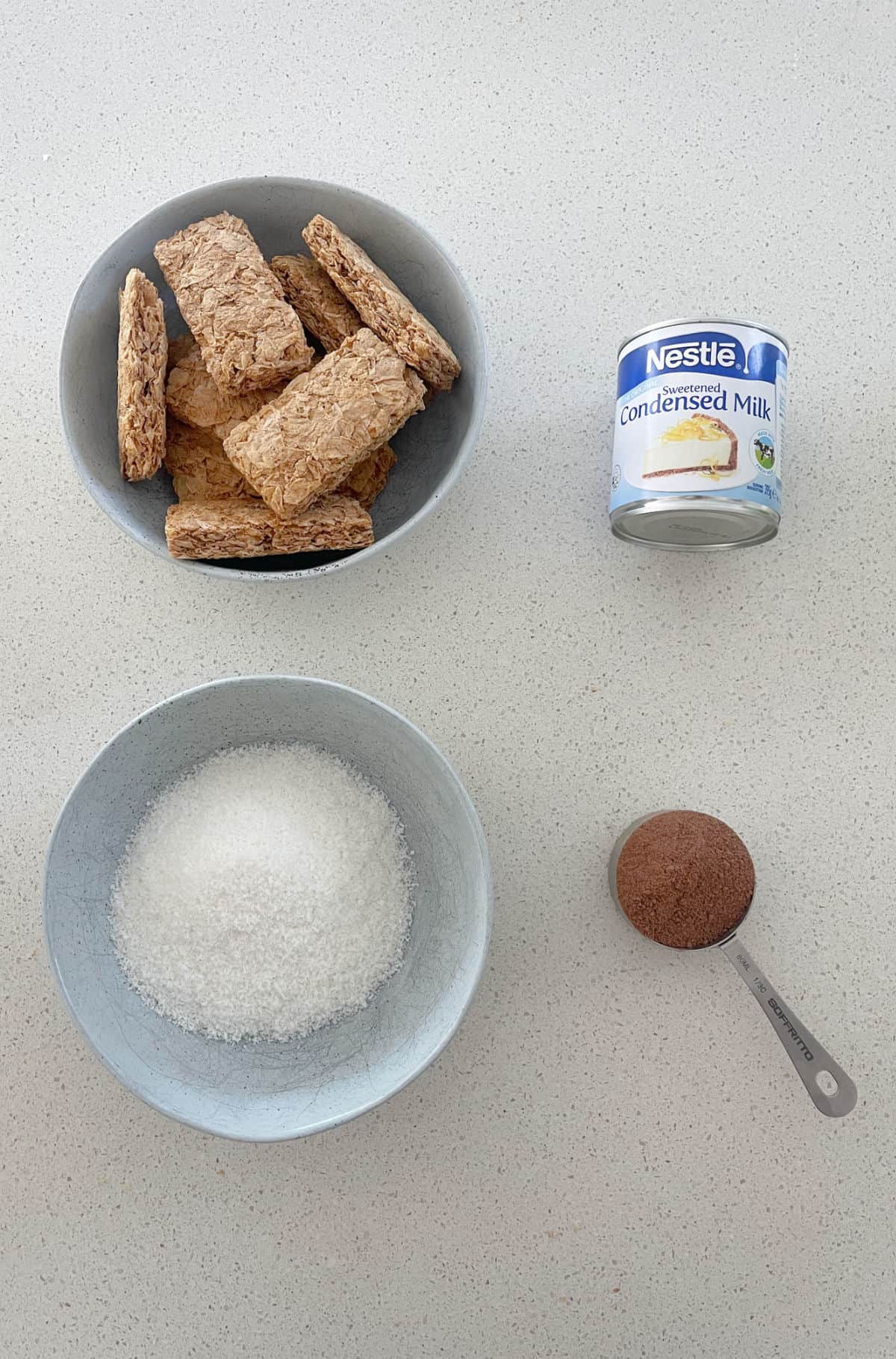 4 ingredients to make Weet-Bix and Milo Balls on a speckled bench top.