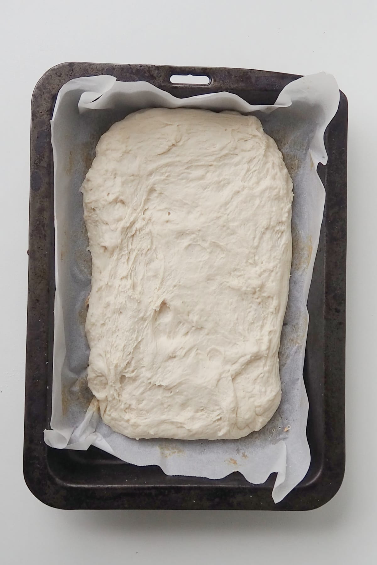 Focaccia dough in a baking tray.