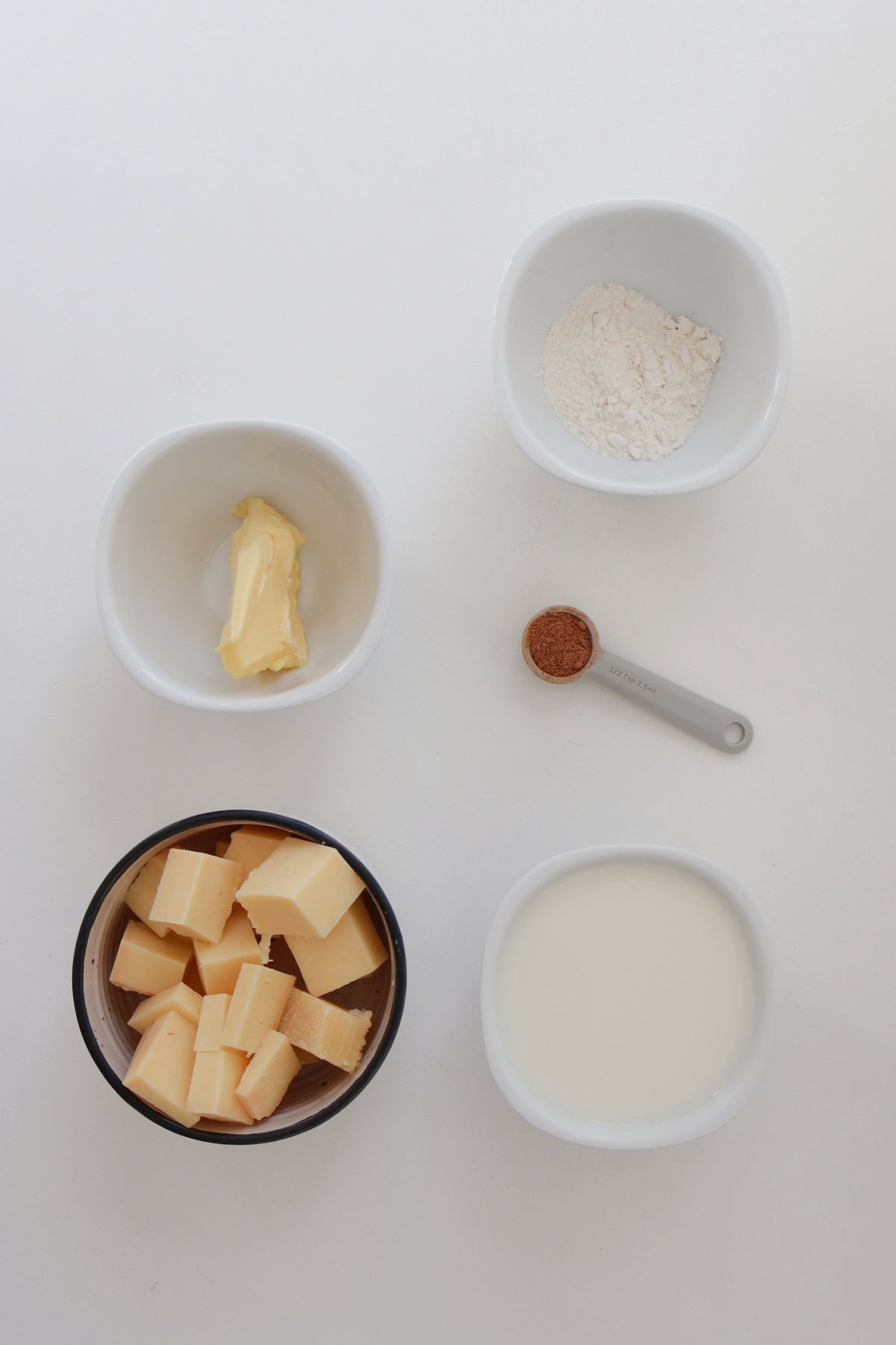 Ingredients to make cheese sauce on a white bench.