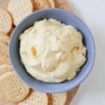 Overhead view of corn relish dip in a blue bowl surrounded by crackers.